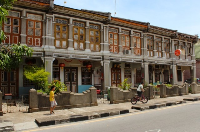 Ochre tones of a row of colonial era shophouses with local boys heading home. Armenian Street.