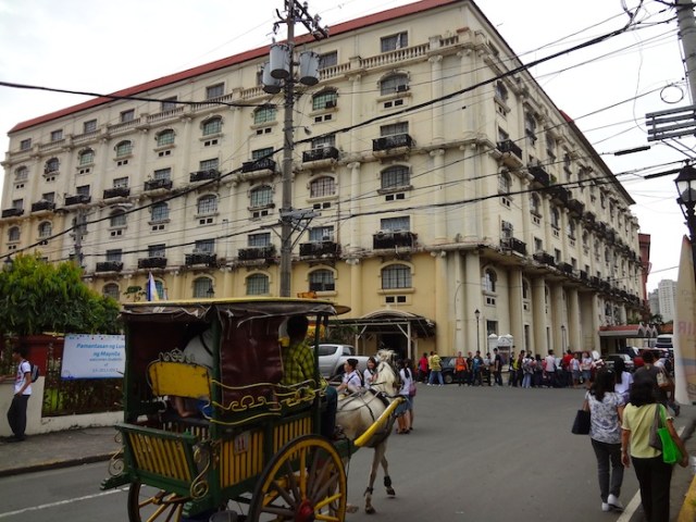 Traditional calesa and university students in the background.