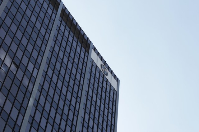 And misses completely, as a shot fires from atop the BMW headquarters and takes the sniper out…