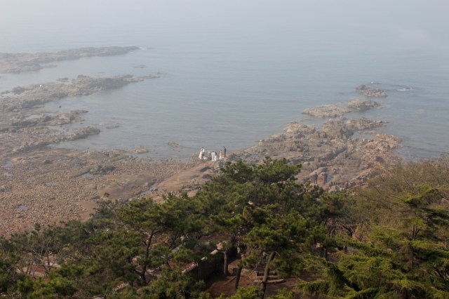 View from the Tower of a wedding photoshoot on the rocky coastline.